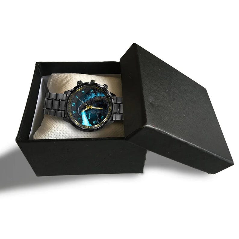K&ouml;nnte beinhalten: Eine schwarze Armbanduhr mit blauem und schwarzem Zifferblatt mit Wasserfalldesign, pr&auml;sentiert in einer schwarzen Geschenkbox. Die Uhr hat ein schwarzes Metallarmband und goldfarbene Akzente.