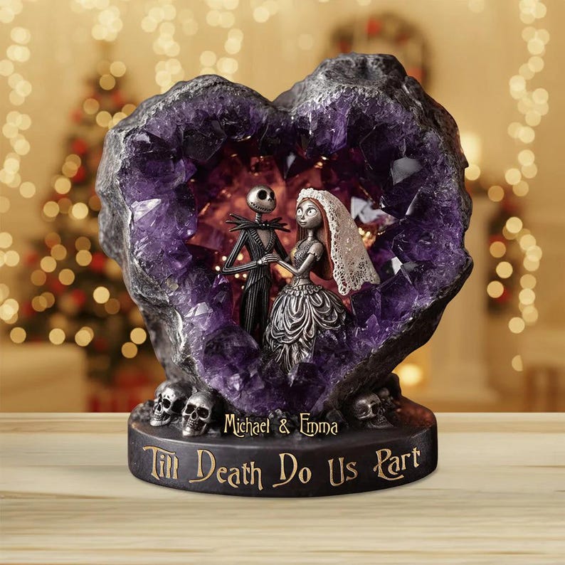 May include: A decorative sculpture featuring Jack Skellington and Sally from The Nightmare Before Christmas, inside a heart-shaped amethyst geode. The base reads "Till Death Do Us Part" with the names "Michael & Emma". Skulls are at the base.