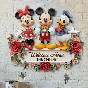 May include: A wall-mounted key holder featuring Mickey Mouse, Minnie Mouse, and Donald Duck. The design includes red roses, floral accents, and the text "Welcome Home THE SMITHS". Includes key hooks.