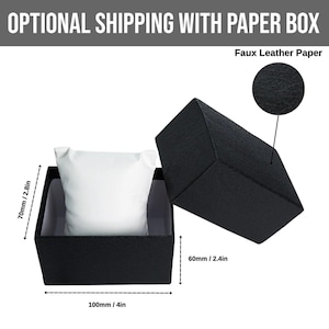 May include: Black watch box with a white pillow inside. The box is open, revealing the interior. The dimensions are 4 inches long, 2.4 inches wide, and 2.8 inches high. The text "Faux Leather Paper" is visible.