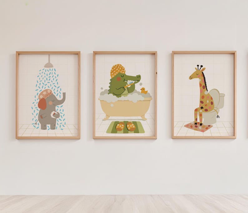 May include: Three framed art prints featuring cartoon animals in a bathroom setting. An elephant under a shower, a crocodile in a bathtub, and a giraffe on a toilet. Each print has a light wood frame and a neutral background.