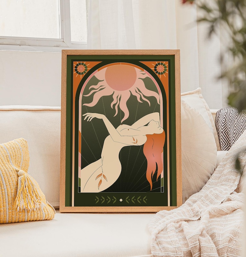 May include: A framed art print featuring a stylized illustration of a nude figure with flowing red hair, reaching towards a sunburst design. The artwork is set against a dark green background with decorative elements and a wooden frame.