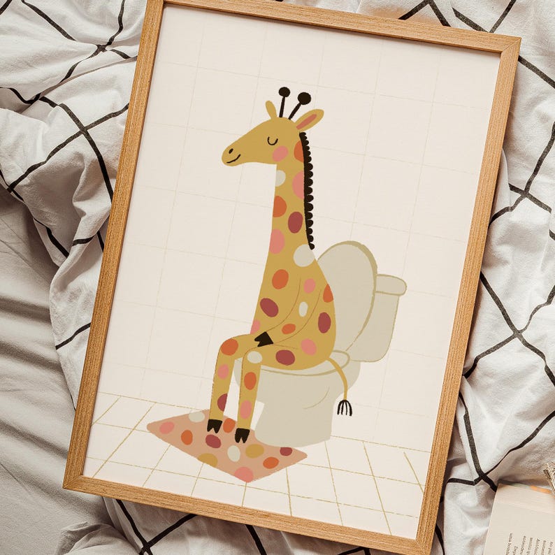 May include: A framed art print featuring a whimsical illustration of a giraffe sitting on a toilet. The giraffe has a yellow body with brown and pink spots. The background is a light beige with a grid pattern, and the frame is made of light wood.