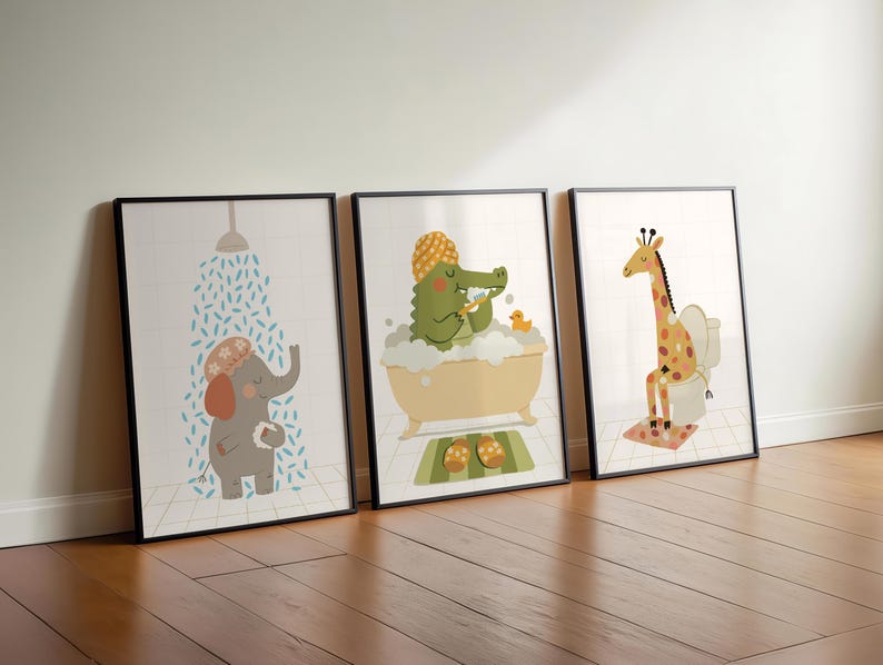 May include: Three framed art prints featuring cartoon animals in a bathroom setting. An elephant takes a shower, a crocodile bathes, and a giraffe sits on a toilet. The prints have black frames and are set against a white wall and wooden floor.