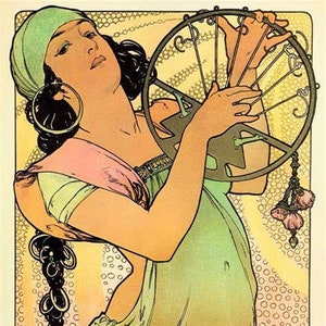 May include: A woman in a green and pink dress plays a musical instrument with a circular frame. The instrument has a series of strings and is decorated with intricate details. The woman's hair is long and dark, and she wears a green headscarf and large earrings.