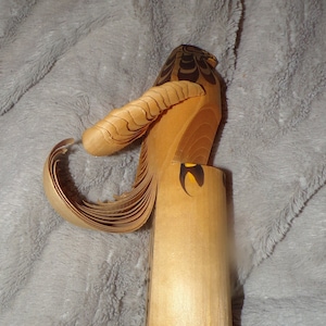 May include: A wooden bird sculpture with a carved tail and black and yellow painted details. The bird is standing on a wooden base.