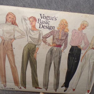 May include: Vintage Vogue's Basic Design sewing pattern featuring illustrations of five different women's outfits. The outfits include high-waisted pants, blouses, and a plaid shirt. The pattern cover is off-white with the text "Vogue's Basic Design".