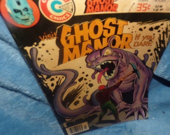 Peut inclure: Une couverture de bande dessinée représentant un monstre violet avec une grande gueule et une longue langue. Le monstre tient une pioche et se tient sur une surface rocheuse. Le texte sur la couverture dit "Visitez Ghost Manor si vous osez".