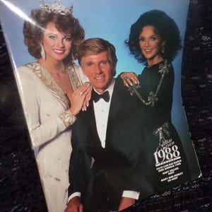 May include: A vintage Miss America 1988 program featuring a photo of the winner, Kaye Lani Rae Rafko, with hosts Gary Collins and Mary Ann Mobley.