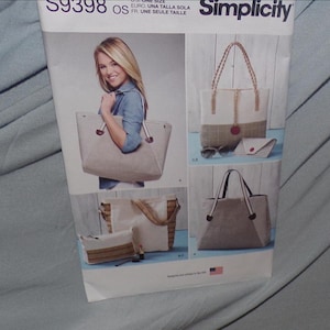 May include: Simplicity sewing pattern featuring tote bags. The bags have various designs, including striped and solid fabrics, with different handle styles. One bag is held by a person. The pattern includes a small matching pouch.