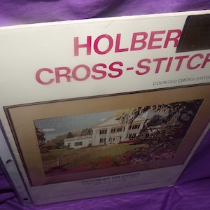 May include: Holber Cross-Stitch counted cross stitch pattern for Victorian Splendor. The pattern features a white house with a green lawn and trees.