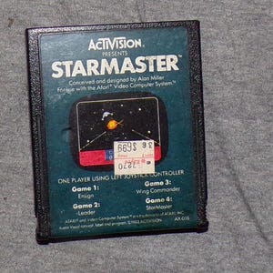 May include: A vintage Atari video game cartridge for StarMaster, designed by Alan Miller. The cartridge is blue and black with a sticker on the front that says "669$ 98".
