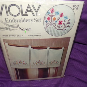 May include: A cross stitch embroidery set for a Noren, a traditional Japanese room divider. The set includes three panels with a floral design in shades of red, orange, yellow, blue, and green. The package includes instructions and a size of 80cm x 40cm.