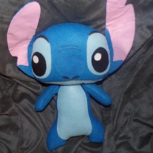 Puede incluir: Un peluche del personaje Stitch de la pel&iacute;cula animada Lilo & Stitch. El peluche azul tiene grandes ojos negros con reflejos blancos, grandes orejas rosas y una barriga azul claro. El juguete est&aacute; hecho de tela suave.