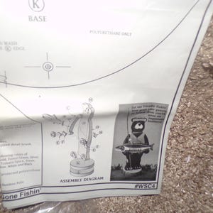 May include: A white paper assembly instruction sheet for a wooden bear craft project. The document features a line drawing assembly diagram, a black and white photograph of a finished bear holding a fish, and the text Gone Fishin' and #WSC4.