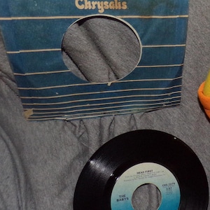 May include: A 45 RPM vinyl record by The Babys, titled "Head First" on the Chrysalis label. The record is blue and black with a butterfly logo.