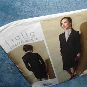 May include: A sewing pattern for a black double-breasted coat with a white collared shirt. The pattern is called "Lialia" by Julia Alarcon, Vogue Patterns Designer Original.