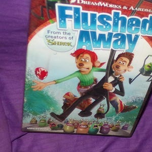 May include: DVD cover for the animated film "Flushed Away" featuring two characters, a red-haired boy and a tuxedo-wearing rat, against a blue and green background. The film is from the creators of "Shrek".