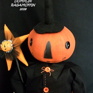 May include: A handmade Halloween doll with an orange pumpkin head, black hat, and black outfit. The doll has button eyes and a painted face. It holds a star-shaped wand. The text "DUMPLIN RAGAMUFFIN 2018" is visible.