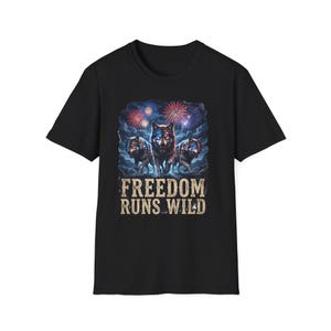 May include: Black t-shirt featuring a graphic of three wolves with American flag markings, set against a backdrop of fireworks. The text "FREEDOM RUNS WILD" is printed below the wolves in a rustic font.