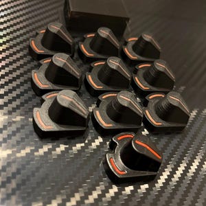 May include: A set of ten black and orange knobs with a raised, pointed top. The knobs have a red accent around the base.