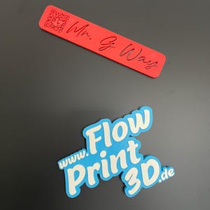 Könnte beinhalten: Ein rotes Plastik-Lesezeichen mit einem QR-Code und dem Text "Mr. G. Way". Ein blaues Plastik-Logo mit dem Text "www.Flow Print 3D.de" ist ebenfalls zu sehen.