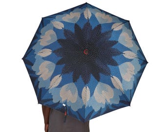 Paraguas azul con diseño geométrico floral tipo mandala, estilo caleidoscopio, impermeable, con dosel simétrico, accesorio de viaje artístico.