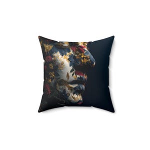 May include: Square throw pillow featuring a floral design on a sculpted face. The pillow has a dark blue background and the face is adorned with red, yellow, blue, and gold flowers. The pillow is square.