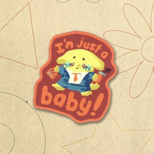 May include: A red and orange sticker with a cartoon yellow dog wearing a blue suit and a red tie. The dog has teary eyes and is holding a briefcase and a cup of coffee. The text on the sticker reads "I'm just a baby!"