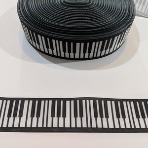 May include: Black and white piano key ribbon. The ribbon is black with white piano keys printed on it.