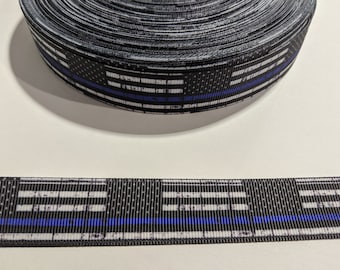 May include: Black and white ribbon with a blue line, resembling a distressed American flag with a thin blue line. The ribbon is rolled up and a section is laid out flat.