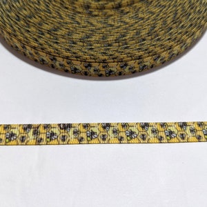May include: A roll of yellow ribbon featuring a repeating pattern of bees and honeycomb. The ribbon is approximately 1.3 cm wide, ideal for crafts, gift wrapping, or other decorative purposes.