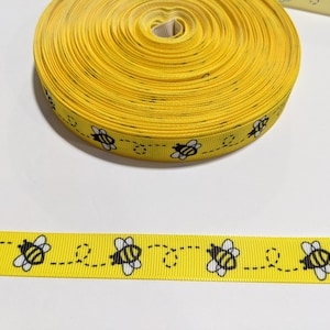 May include: Yellow ribbon with a repeating pattern of black bees flying along a dotted line.