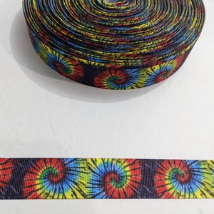 May include: A roll of black and white tie-dye ribbon with red, yellow, and blue swirls. The ribbon is 1 inch wide and is perfect for adding a pop of color to crafts and projects.