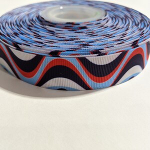 May include: A roll of blue, white, red, and black patterned ribbon with a wavy design.