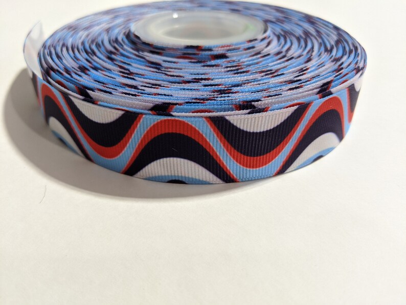 May include: A roll of blue, white, red, and black patterned ribbon with a wavy design.