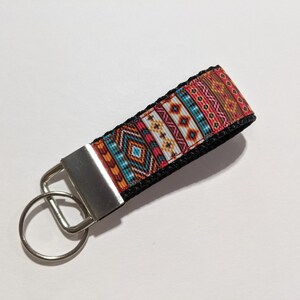 May include: A black key chain with a colorful geometric pattern and a silver key ring.
