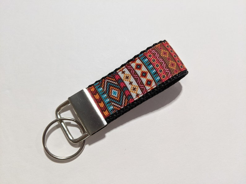 May include: A black key chain with a colorful geometric pattern and a silver key ring.