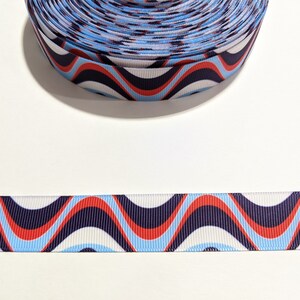 May include: A roll of blue, red, and white patterned ribbon with a wavy design. The ribbon is 1 inch wide.