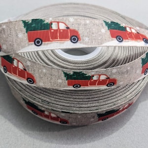 May include: A roll of beige ribbon with a repeating pattern of red pickup trucks carrying green Christmas trees. The ribbon has a subtle snowflake pattern.