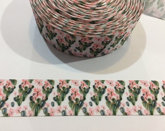 May include: A roll of white ribbon with a repeating pattern of pink cactus flowers and green cactus plants.