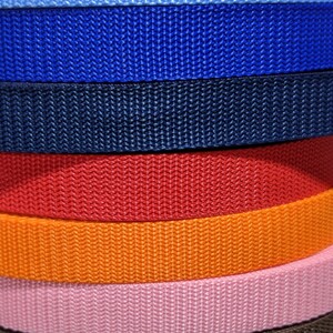 May include: A stack of 13 different colored webbing straps. The straps are all the same width and are arranged in a stack from top to bottom. The colors are black, gray, light blue, blue, navy blue, red, orange, pink, brown, purple, royal blue, and yellow.