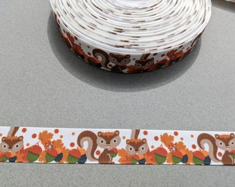 May include: White ribbon with a repeating pattern of brown squirrels and orange leaves. The ribbon is 1 inch wide.