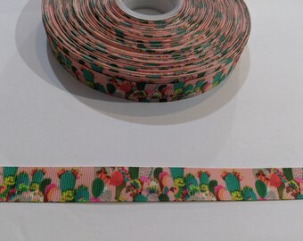 May include: Pink ribbon with a repeating pattern of green, pink, and yellow cacti. The ribbon is rolled up and the pattern is visible on the side.