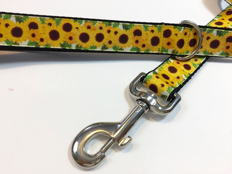 May include: A black and yellow dog leash with a sunflower print and a silver clip.