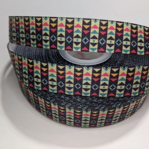 May include: A roll of black and white ribbon with a colorful geometric pattern. The pattern features red, yellow, blue, and green triangles and squares.