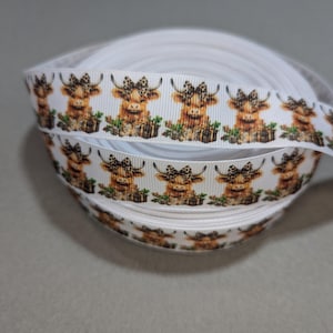 May include: White ribbon with a repeating pattern of brown and white Highland cows wearing bows. The cows are on a white background.