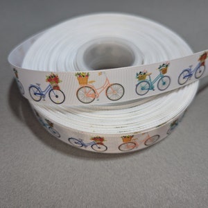 May include: White ribbon with a repeating pattern of colorful bicycles with baskets of flowers.