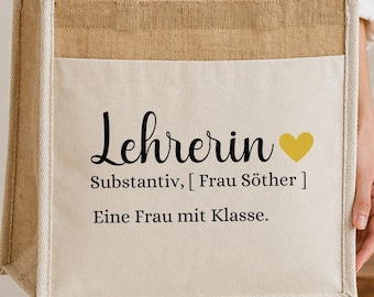 Könnte beinhalten: Eine rechteckige Tragetasche aus naturfarbenem Jute-Gewebe und cremefarbenem Canvas. Auf der Vorderseite befindet sich ein schwarzer Aufdruck mit dem Text "Lehrerin", "Substantiv, [ Frau Söther ]" und "Eine Frau mit Klasse." sowie ein gelbes Herz.
