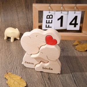K&ouml;nnte beinhalten: Holzfigur eines Elefanten mit einem roten Herzen, personalisiert mit den Namen "Jason" und "Linda". Die Figur ist ein Valentinstagsgeschenk.